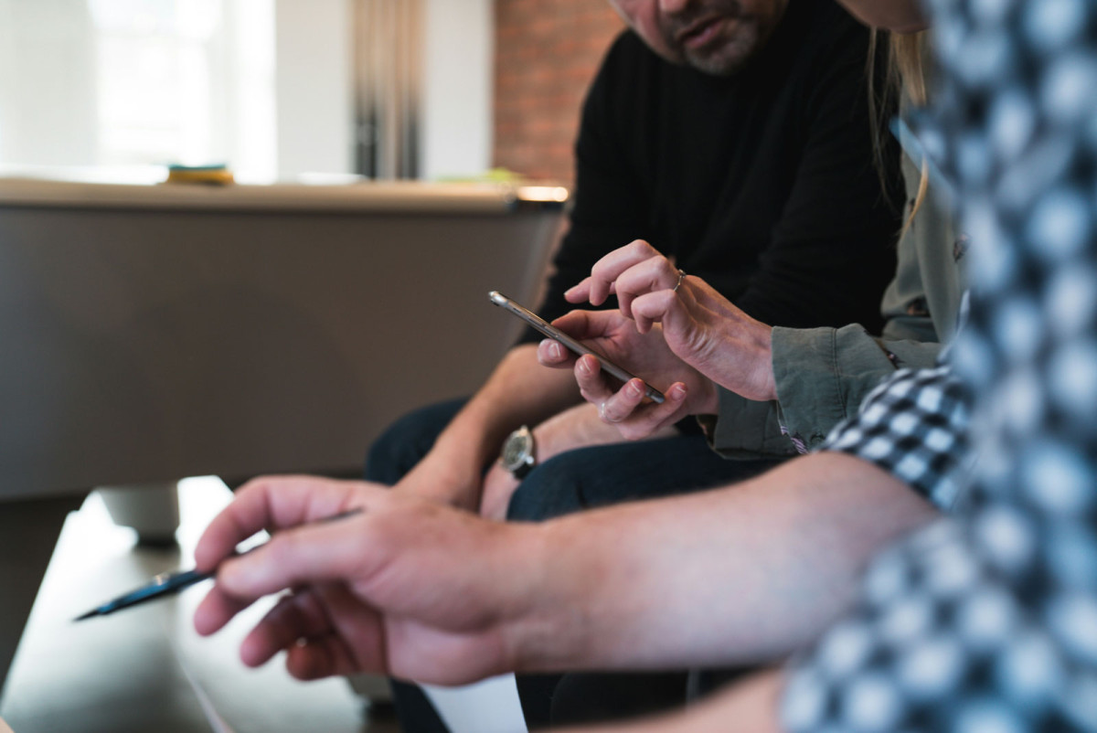 WithCommunity Organizing Team members working together, one using a phone while another holds a pen